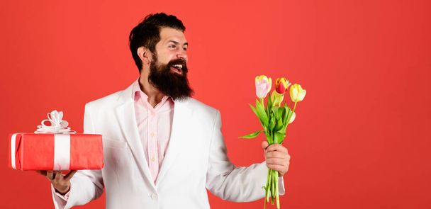 Uomo sorridente con regalo e bouquet di tulipani. Regalo per il giorno delle donne, San Valentino, Compleanno. - Foto, immagini
