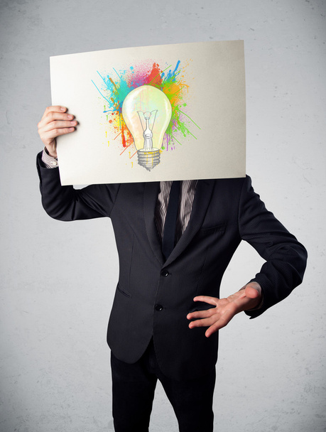 Businessman holding a cardboard with paint splashes and lightbul - Foto, Imagem