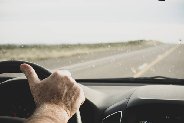 Male driver hand holding the steering wheel on road. - Valokuva, kuva
