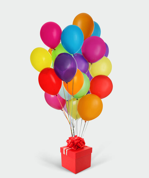Beautiful gift box and bunch of colorful balloons on white background - Fotoğraf, Görsel
