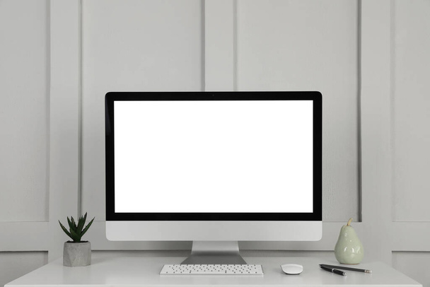 Modern computer, decor and office supplies on white wooden table near molding wall - Foto, immagini
