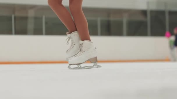 Primer plano en los patines de hielo mientras se realiza la figura girando en la pista de hielo - Imágenes, Vídeo