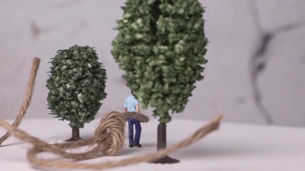Miniaturowy człowiek przywiązany do miniaturowego drzewa i liny. Koncepcja męskości wymuszonej w społeczeństwie. - Materiał filmowy, wideo