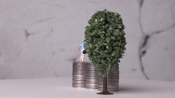 Миниатюрные гольфисты стоят на куче монет и миниатюрном дереве. Миниатюры и груды монет с бизнес-концепциями.  - Кадры, видео