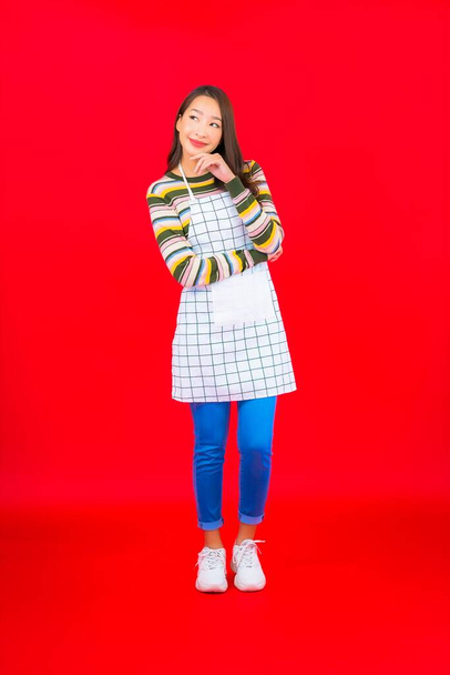 Портрет красива молода азіатка носить фартух на червоному тлі
 - Фото, зображення