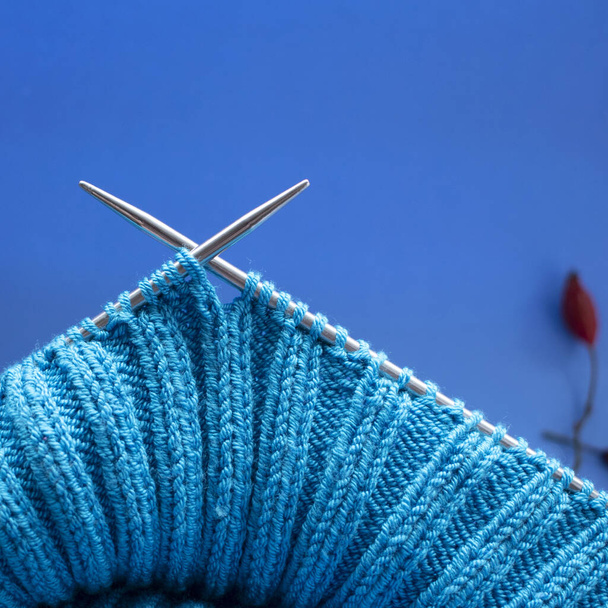 aiguilles à tricoter, toile bleue, crochet gros plan, fond bleu - Photo, image