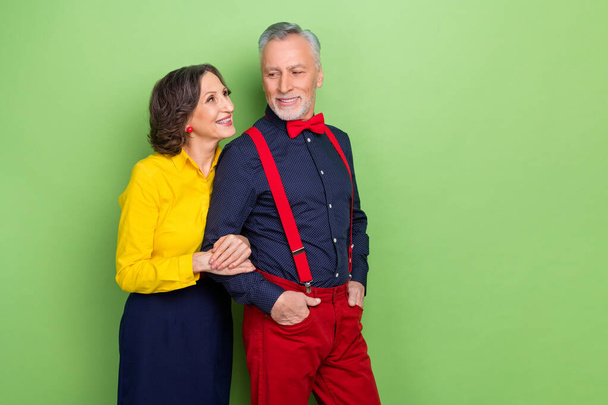 Portrait of two attractive aged people hold arm look each other trust support isolated on green color background - Foto, imagen