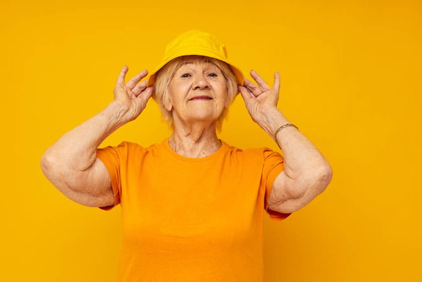 elderly woman in yellow t-shirts hat posing isolated background - 写真・画像