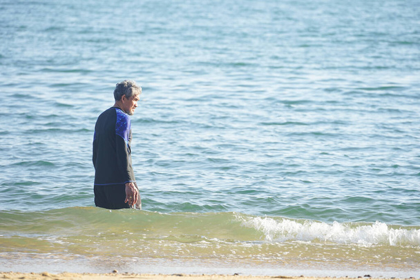 ανώτερος άνθρωπος με κολύμπι φορούν περπάτημα στη θάλασσα στην παραλία    - Φωτογραφία, εικόνα