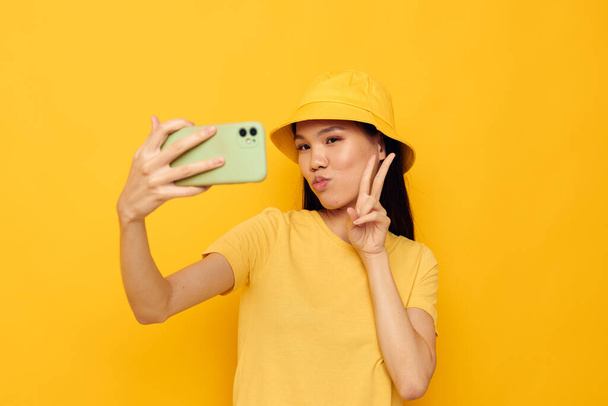 woman holding a phone posing lifestyle technology yellow background unaltered - Photo, Image