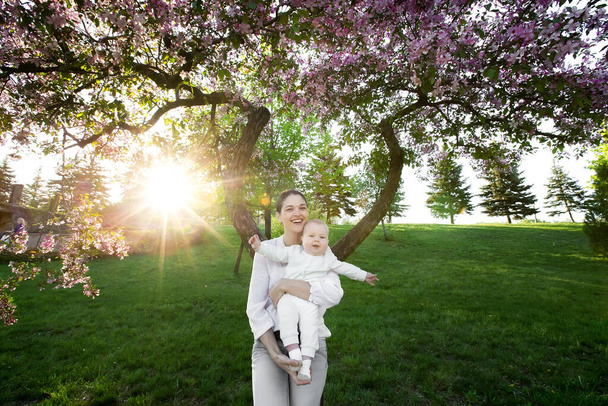 Mooie moeder en baby buiten. De natuur. Schoonheid mama en haar kind spelen in het park. - Foto, afbeelding