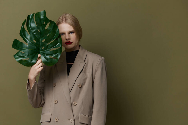 портрет женщины зеленый пальмовый лист пальто яркий макияж изолированный фон - Фото, изображение