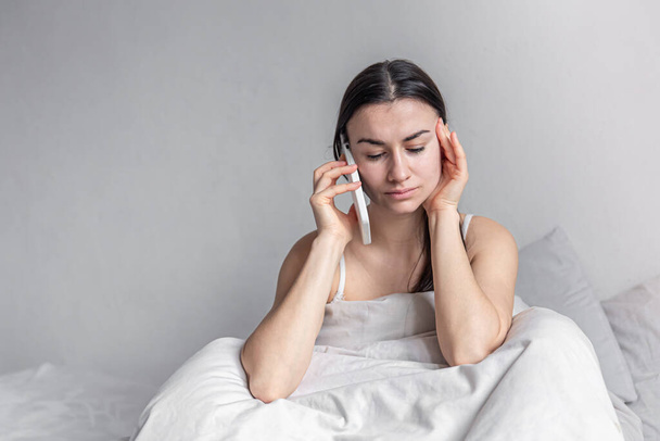 Eine junge Frau am Morgen mit Smartphone im Bett. - Foto, Bild