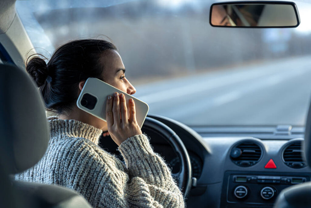 Young woman talking on the phone while driving a car. - Photo, image
