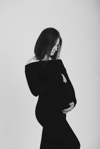 Black and white photo of a pregnant woman on a white background. Silhouette - Foto, afbeelding
