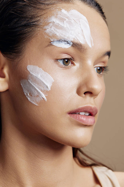 woman applying a soothing face mask cosmetic beige background - Фото, зображення