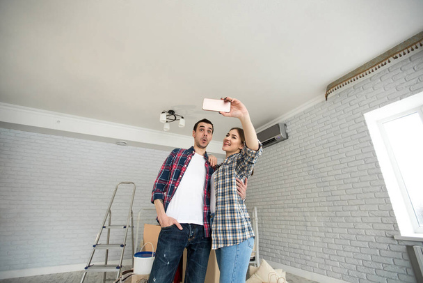 Young couple makes selfie while moving to a new apartment. Moving newlyweds to new housing - Foto, afbeelding
