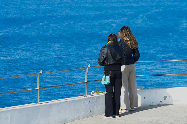 Twee meisjes bewonderen de oceaan op een klif - Foto, afbeelding