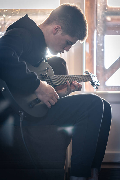 Un ragazzo suona la chitarra elettrica nella sua stanza. - Foto, immagini