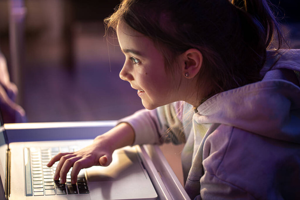 A little girl uses a laptop late at night. - Foto, imagen