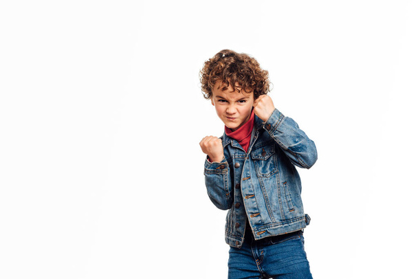 Boy clenching fists ready to fight while standing over an isolated white background. - Фото, изображение