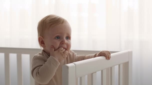 Dentição em bebês. Criança infantil adorável em pé na cama e mastigar os dedos - Filmagem, Vídeo