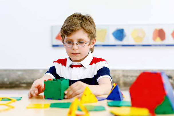 Szczęśliwy chłopiec z okularami bawiący się w budowaniu i tworzeniu figur geometrycznych, nauce matematyki i geometrii - Zdjęcie, obraz