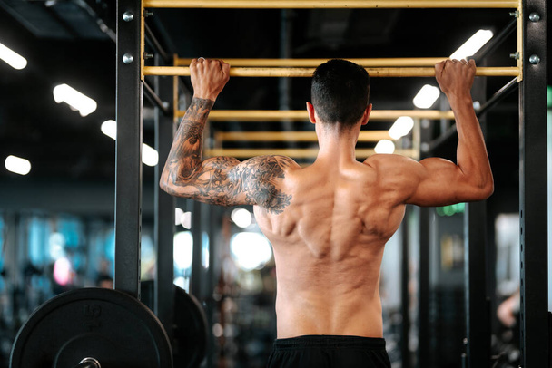 Athlete muscular fitness manl pulling up on horizontal bar in a gym - Foto, imagen