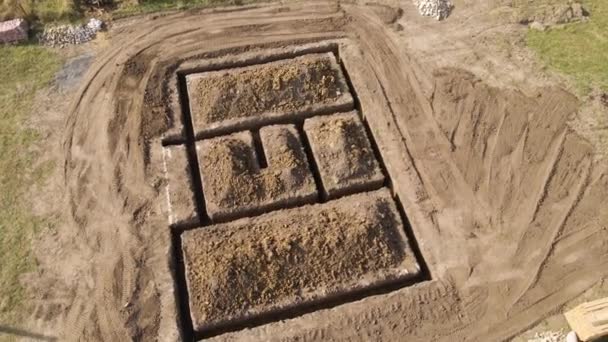 Uitgraven loopgraaf voor de bouw van nieuwe huis betonnen fundering op bouwplaats - Video