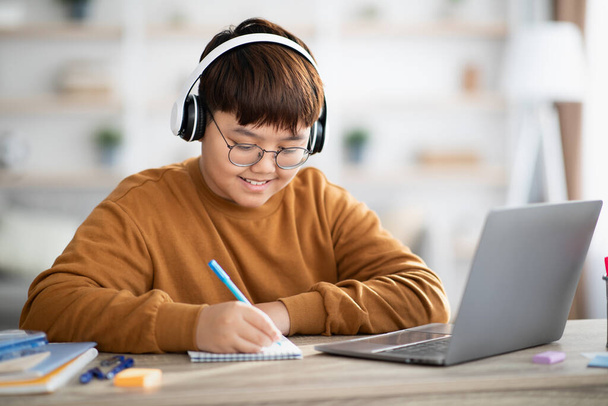 Hymyilevä aasialainen poika koululainen, jolla on online-oppitunti kotoa - Valokuva, kuva