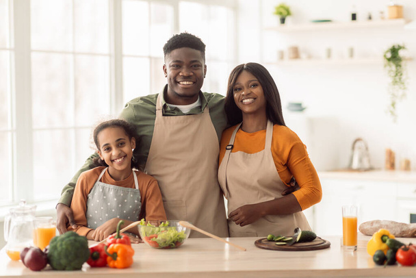 Χαρούμενη μαύρη οικογένεια αγκαλιάζει μαγείρεμα μαζί στέκεται στην κουζίνα - Φωτογραφία, εικόνα