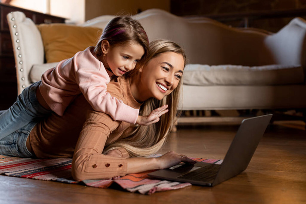 Souriant femme et fille à l'aide d'un ordinateur portable agitant la main - Photo, image