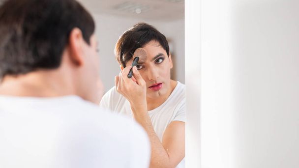 A homosexual man puts on makeup in front of a mirror. Male transgender. - Fotó, kép
