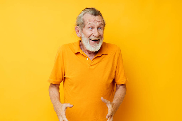 Senior grey-haired man yellow shirt posing emotions isolated background - Фото, изображение