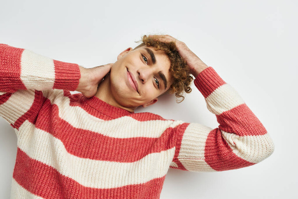 handsome guy in a striped sweater posing light background - Foto, afbeelding