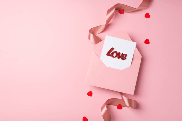 Sevgililer Günü dekorasyonunun en üst görüntüsü kırmızı kalpler kıvırcık ipek kurdele açık pembe zarf kağıt kart ve yazılı aşk izole edilmiş pastel pembe arka planda kopyalanmış - Fotoğraf, Görsel