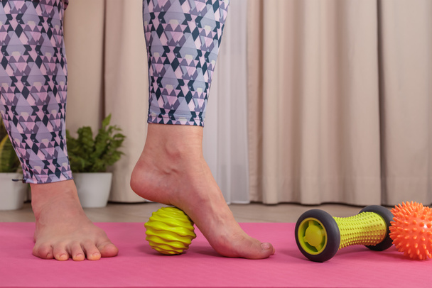 Detailní záběr na nohy dívky, jak si masíruje nohy zeleným míčkem - Fotografie, Obrázek