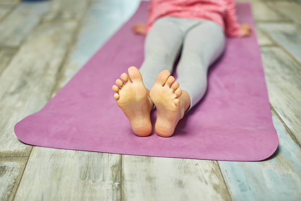 Close up of feet leg Little girl doing stretching exercises, practicing yoga on fitness mat at home, Playing sports, Healthy lifestyle. Kids sport home quarantine - Photo, Image