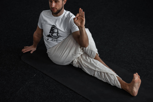 Profi fiatalember jógázik a szőnyegen. Edző nyújtás és mutatja rendben. - Fotó, kép