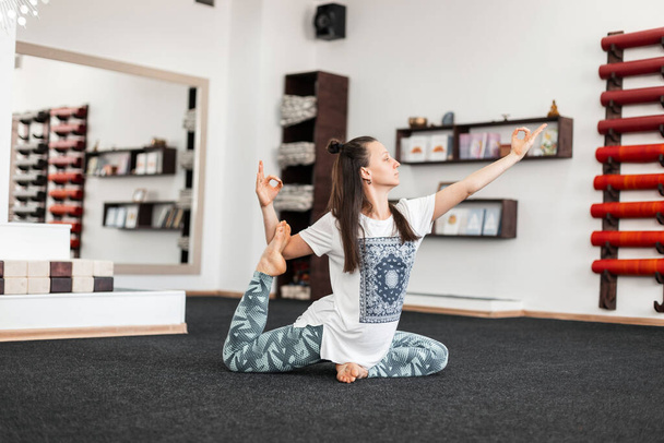 Professionele jonge vrouw doet oefeningen in de fitnessruimte op de mat. Sportief meisje oefent yoga, stretching of pilates. - Foto, afbeelding