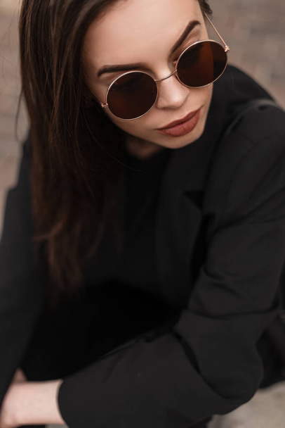 Close-up retrato de bela jovem mulher de negócios elegante em moda outerwear preto com óculos de sol frescos - Foto, Imagem