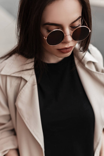 Fashionable young sexy woman in round stylish sunglasses in trendy casual wear on street in city. Fresh portrait pretty attractive girl in spring outfit outdoors. Beauty lady. - Fotografie, Obrázek