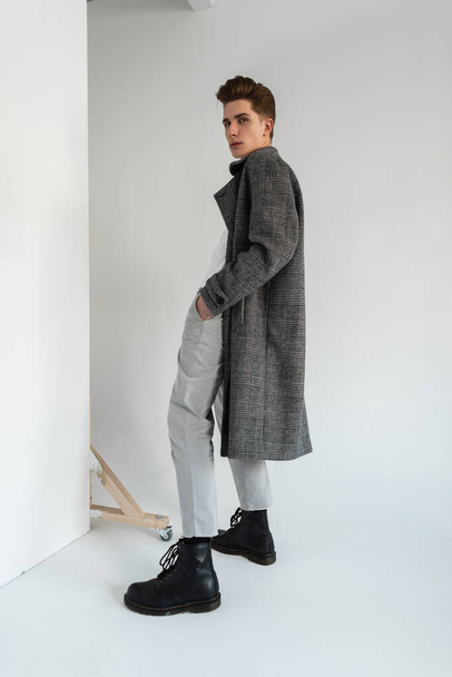 Модний хлопець у стильному класичному пальто з штанами та черевиками в студії
 - Фото, зображення