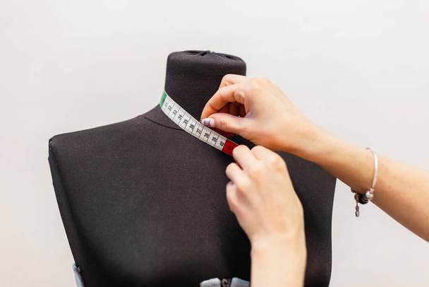 Fashion designer measuring a mannequin. Professional dressmakers dummy with measuring tape. Close-up female hands with centimeter - Foto, Bild