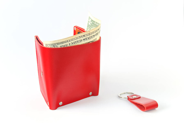 Leuchtend rote Lederhandtasche mit Geld auf weißem Hintergrund. Horizontale Platzierung. Isoliert. Dollar im Portemonnaie - Foto, Bild