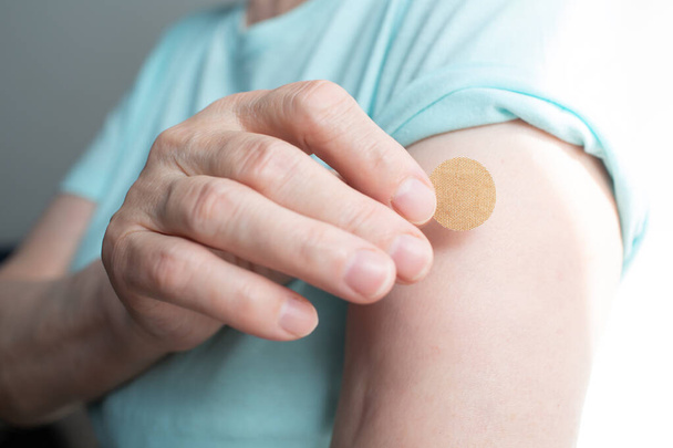Vaccination elderly woman in doctor office with adhesive covid-19 vaccine plaster. - Photo, Image