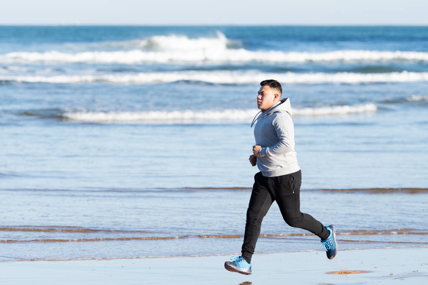 Ισπανόφωνος τρέχει στην παραλία, επικεντρώθηκε στους στόχους του. - Φωτογραφία, εικόνα