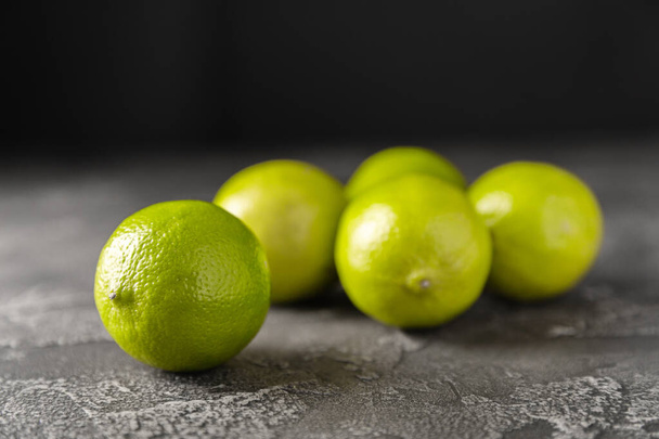 Lime, juicy ripe citrus fruits on a dark background. Ingredients for preparing refreshing drinks and cocktails. Mojito. Selective focus, top view and copy space - Photo, image