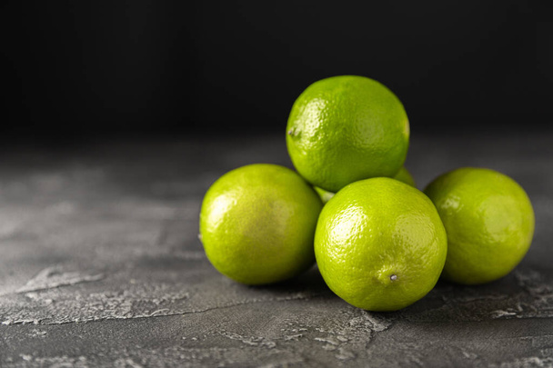 Lime, juicy ripe citrus fruits on a dark background. Ingredients for preparing refreshing drinks and cocktails. Mojito. Selective focus, top view and copy space - Фото, изображение