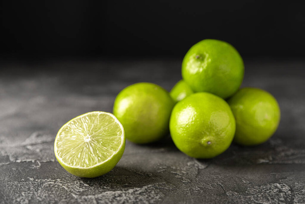 Citron vert, agrumes mûrs juteux sur un fond sombre. Ingrédients pour préparer des boissons rafraîchissantes et des cocktails. Mojito. Mise au point sélective, vue du dessus et espace de copie - Photo, image